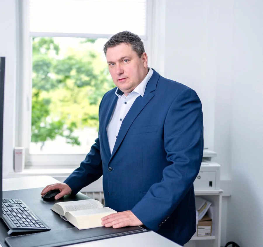 Rechtsanwalt Andreas Meyer bei der Aktenarbeit am Schreibtisch mit aufgeschlagenem Gesetzestext