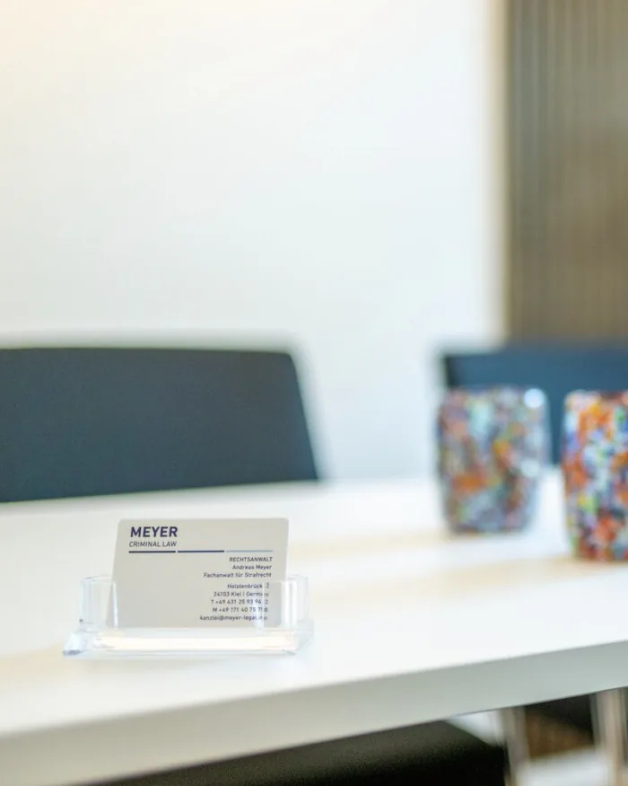 Business card and Murano glass tumblers on the conference table — Meyer Criminal Law, Kiel